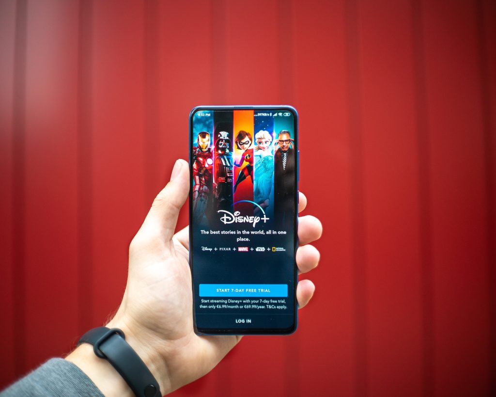 person holding up smartphone with disney+ streaming service open